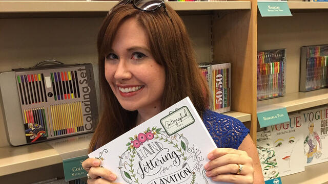 Amy Latta ’02 holding a copy of her book, “Hand Lettering for Relaxation.”
