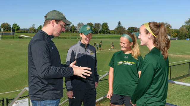 Chemistry professor Dana Ferraris, faculty athletics mentor to the women's soccer team, explains to coach Sandy Lagana and team co-captains Abby Keen and Kristen Upton how he and his wife make the bagels he brings to the team on home-game mornings.