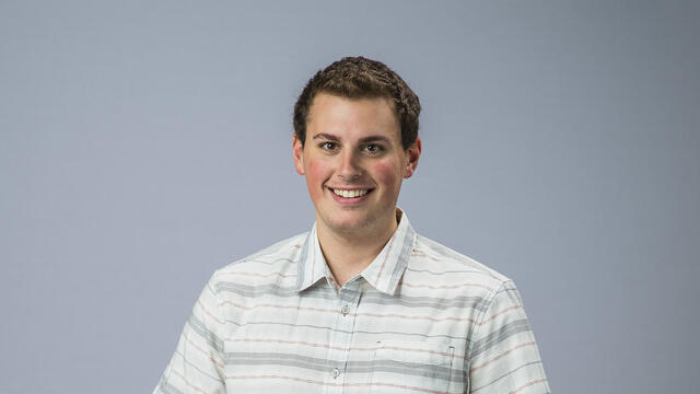 Newman Civic Fellow Atticus standing in front of plain background.