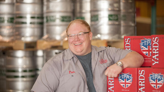 Tom Kehoe standing in front of Yards Brewing inventory.