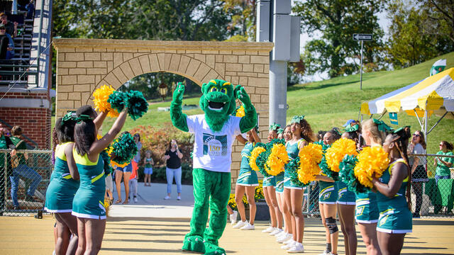 Green Terror mascot with cheerleaders.