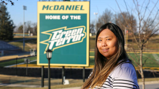 Brianna Myung standing on campus with the McDaniel Home of the Green Terror sign in the background.