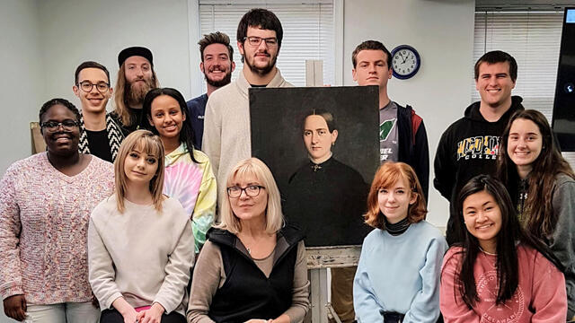 Professor and students gathered around “Portrait of the Lady” painting after restoration.