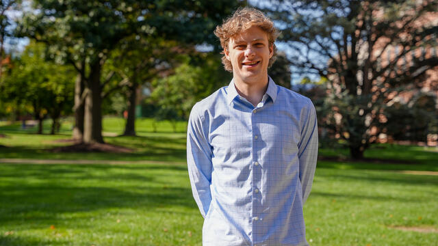 Alum Dominic Byerly posing in a green field.