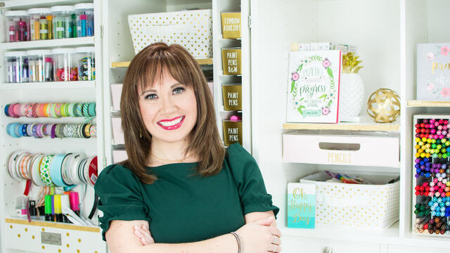 Alumna Amy Latta poses in front of bookshelves.