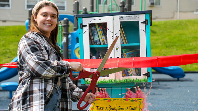 Student Gia K. cuts the ribbon on her new little free library.