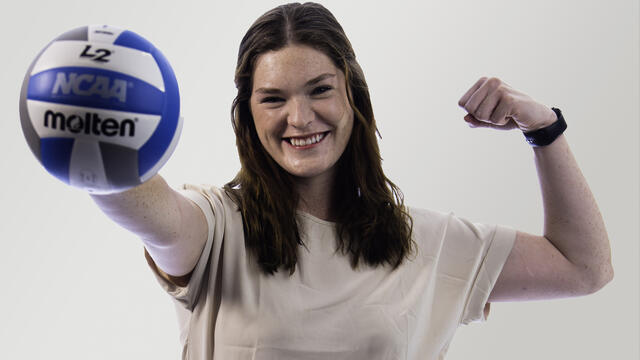Anna Jezerski poses while holding out a volleyball.