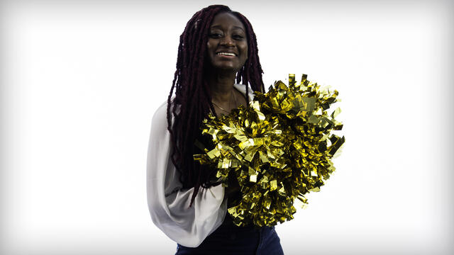 Tracey Ackah holding two gold pompoms.