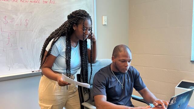 Two students collaborate at a computer.