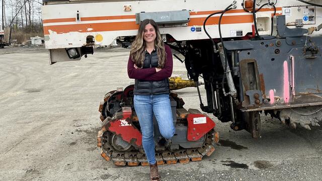 Photo of alum Perri Freeman standing in front of construction machinery.