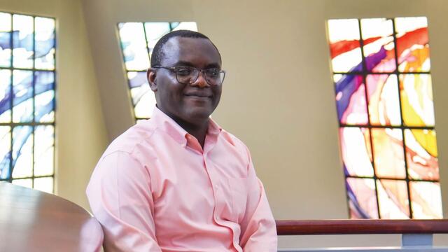 Photo of professor Gerard Keubeung seated in the library next to some books.