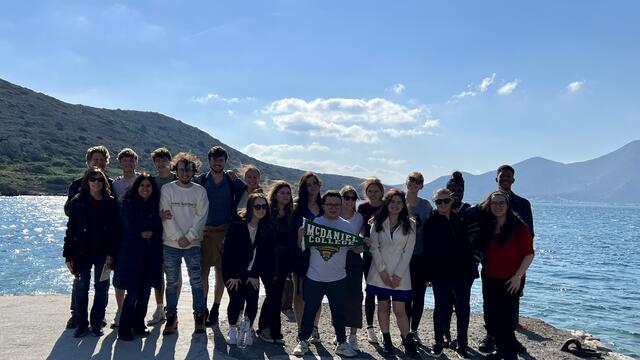 People stand in front of blue sky with water