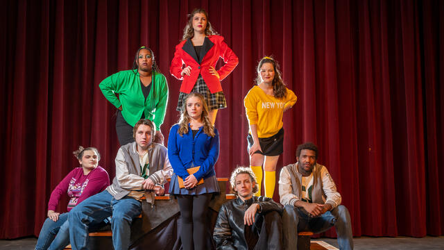 The full cast of Heathers The Musical. They are in vivid colored clothing with sad expressions.