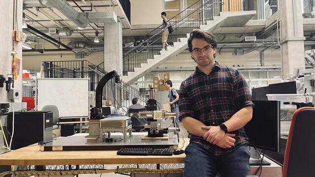 Photo of alum Dimitri Lezcano sitting in a laboratory.