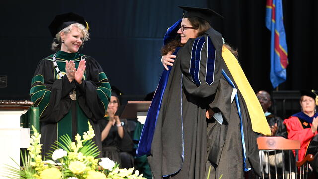 Kerry Duvall hugging Wendy Morris with Julia Jasken looking on at Commencement.