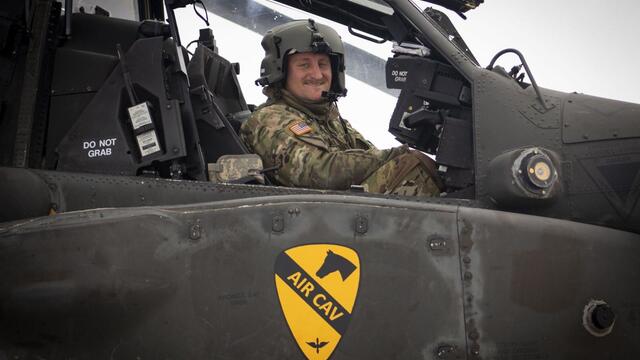 Alum Zach Nibbelink looks at the camera while sitting in an Apache helicopter cockpit.