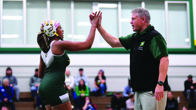 A female wrestler in a McDaniel unitard high-fives coach John Lowe.