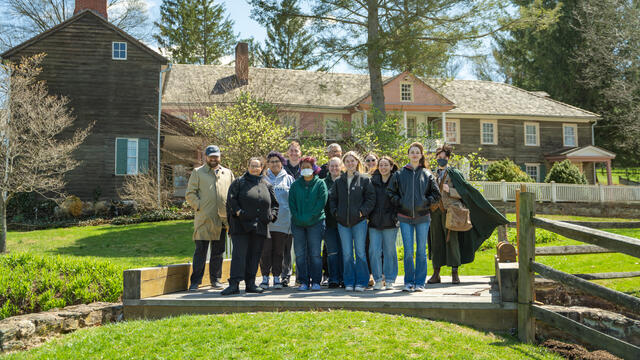Group photo of students and a professor standing outside of Union Mills Homestead house.