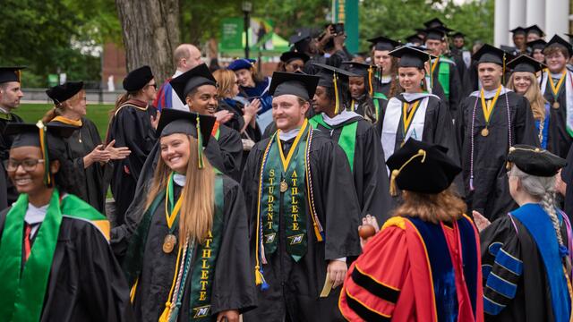 Students in graduation regalia walk in rows