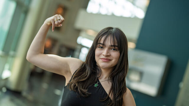 Sabina flexes her arm.