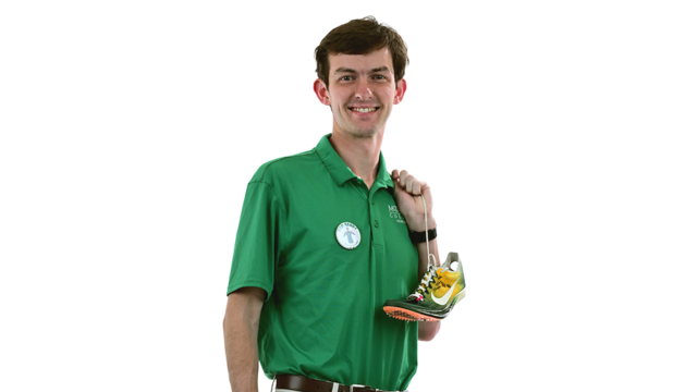 A male student in a McDaniel polo holds a gold medal and track shoes.