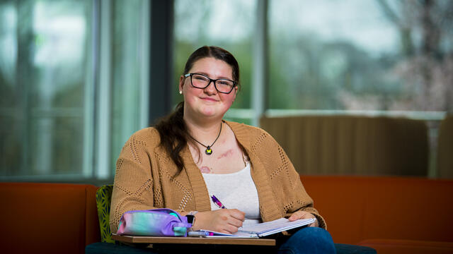 Lauren sits and writes in a notebook.