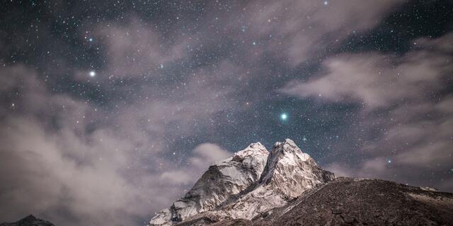Clouds and stars over a mountain