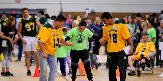 McDaniel students Michael Scott, left, and senior Jared Payne, both lacrosse players, cheer on Tournament of Champions athlete Jason Rivas, a seventh-grader at Montgomery Village Middle School.