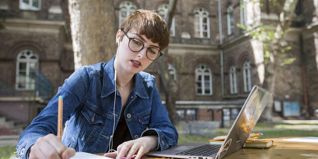 Student writing in notebook outside of Budapest campus.