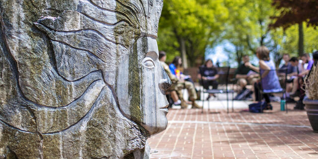 Sculpture outside of Hoover Library with students in background.