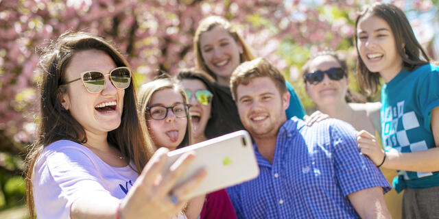 Students taking group selfie outside on campus.