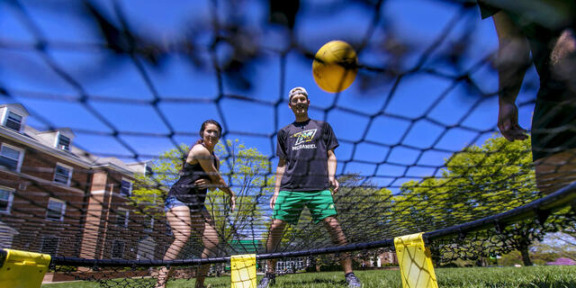 Students playing Spikeball on campus lawn.
