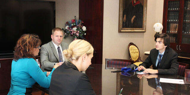 Student in business suit at conference table on Interviewing Day.