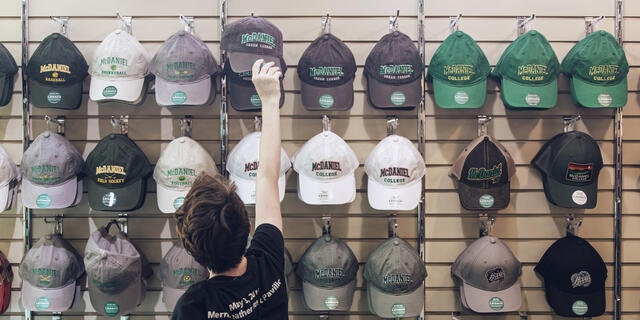 Student selecting McDaniel hat in campus bookstore.