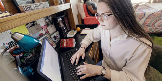 Students on computers in residence hall room.