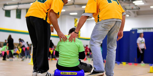 Athletes helping child on scooter at Tournament of Champions