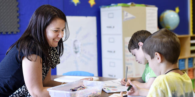 Student interacting at desk with elementary school children.