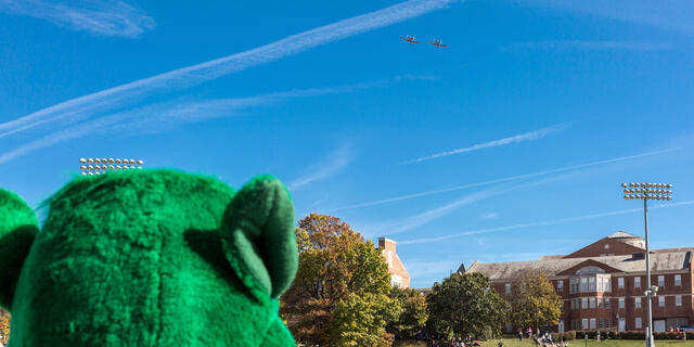 Green Terror mascot looking at campus.