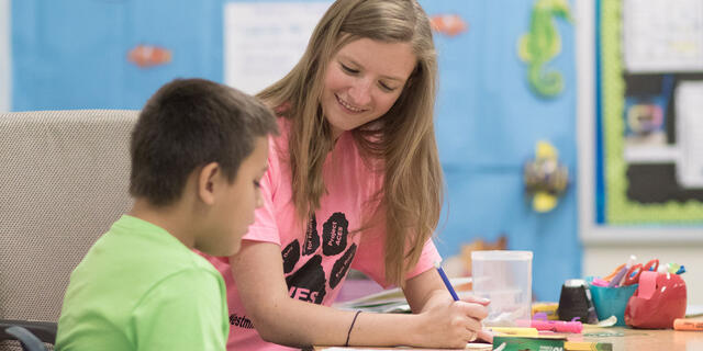 McDaniel student working with elementary student at desk.