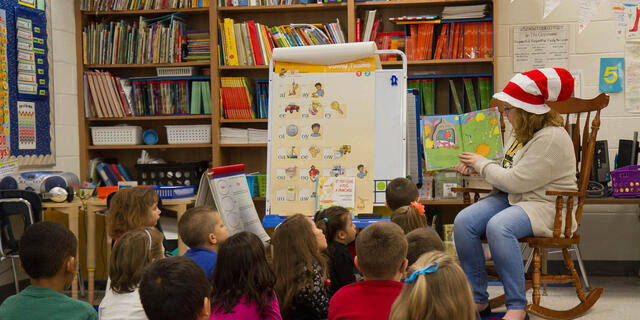 Student reading to a classroom full of elementary school children.