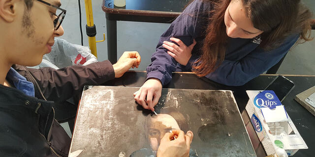 Students participate in the cleaning process of the canvas.