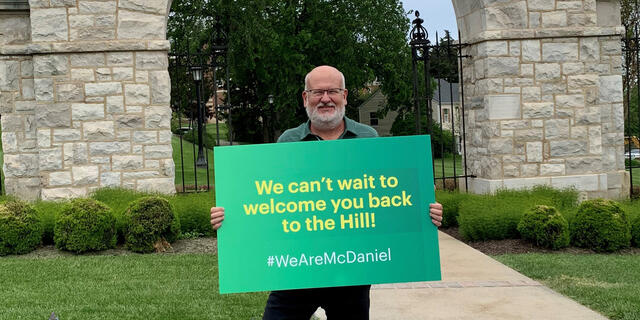 Roger Casey holding sign: We can't wait to welcome you back to the hill