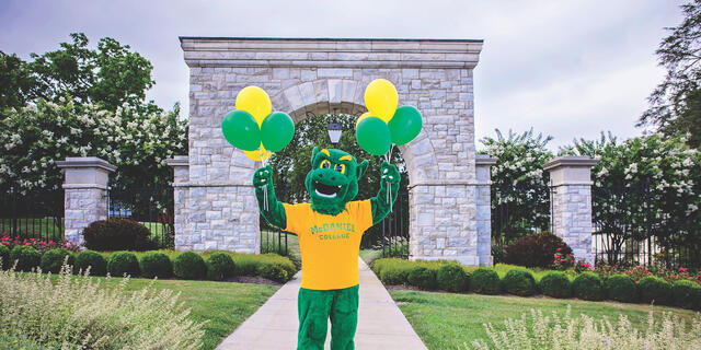 Green Terror holding balloons in front of Arch