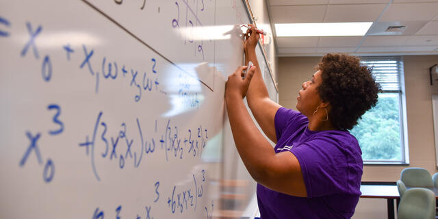 professor writing math equations on white board