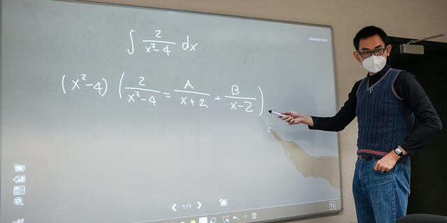 Person writing math equations on white board