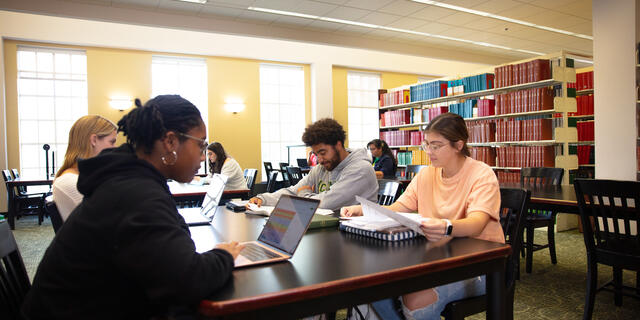 Students work on laptops at a table in McDaniel's Hoover Library.