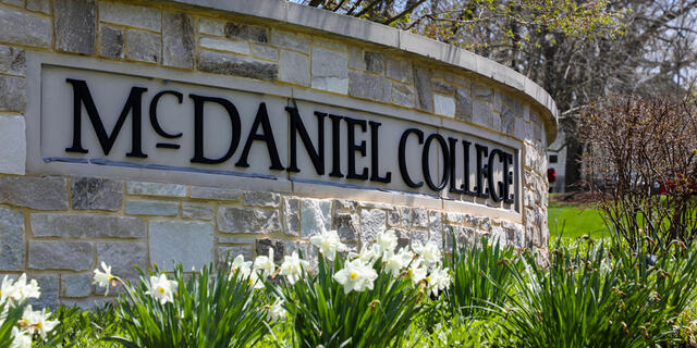 Photo of the stone McDaniel campus sign with flowers in front of it. 