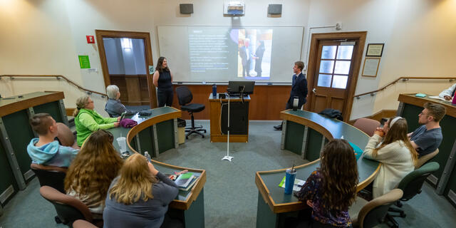 Two students present a PowerPoint on Brexit to a round classroom.