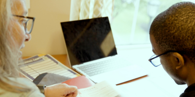 woman and student sit at a desk looking at computer screen