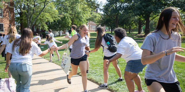 Students laugh as they run through a group of students giving high fives